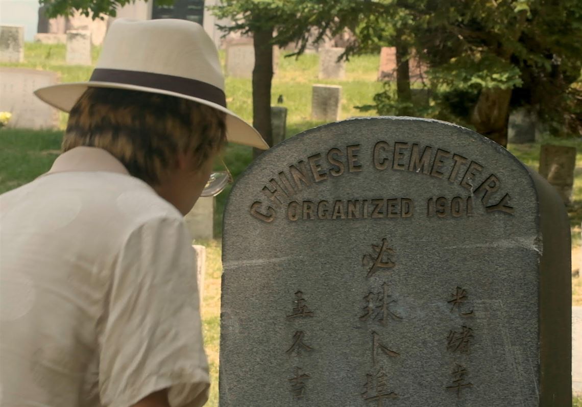 A participant of lights incense at a gravestone in the Chinese section of Homewood Cemetery during a walking tour on Saturday, May 21, 2022. This tour is part of a series of events organized by JADED this spring.