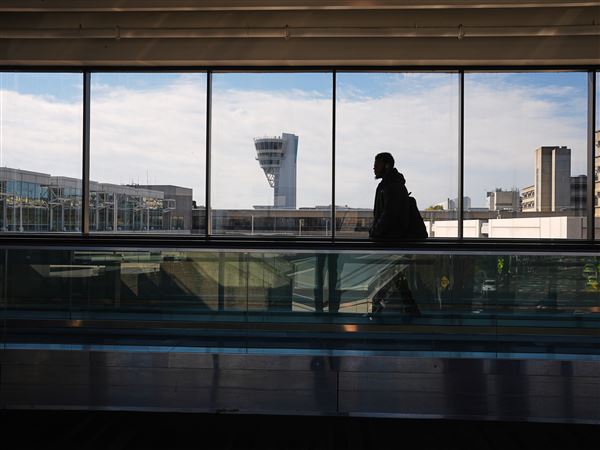 A traveler moves in view of a control tower at Philadelphia International Airport in Philadelphia, Wednesday, Nov. 5, 2025.