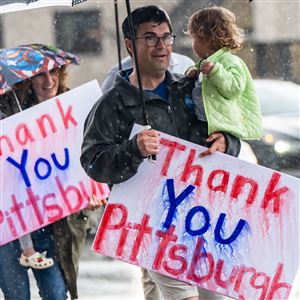 Katie O'Connor follows her husband, Corey O'Connor, across the street carrying their children, Molly and Emmett, where they stood in pouring rain on Wednesday, May 21, 2025, holding homemade signs on the corner of Forward and Murray Avenues in Squirrel Hill, thanking Pittsburgh for voting him in as the Democratic nominee for mayor.  