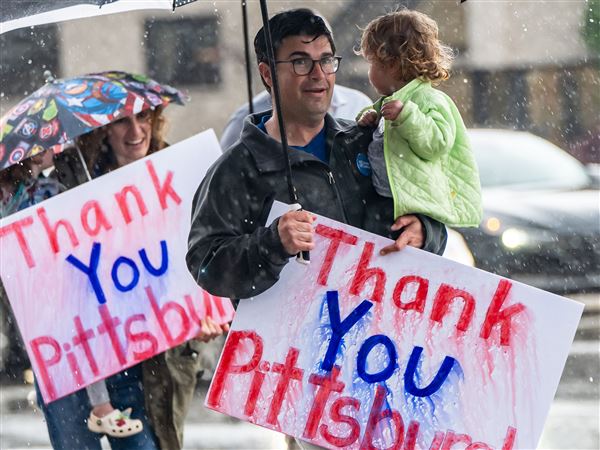 Katie O'Connor follows her husband, Corey O'Connor, across the street carrying their children, Molly and Emmett, where they stood in pouring rain on Wednesday, May 21, 2025, holding homemade signs on the corner of Forward and Murray Avenues in Squirrel Hill, thanking Pittsburgh for voting him in as the Democratic nominee for mayor.  