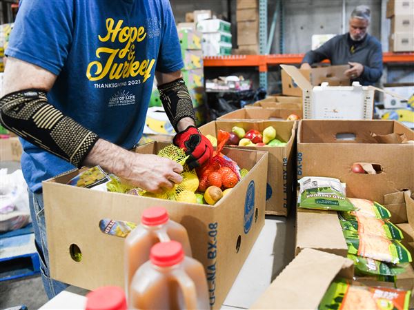 A volunteer at Light of Life Rescue Mission — a homeless shelter and soup kitchen — prepares a box of food in the organization’s food pantry Wednesday, Oct. 29, 2025, on the North Shore.